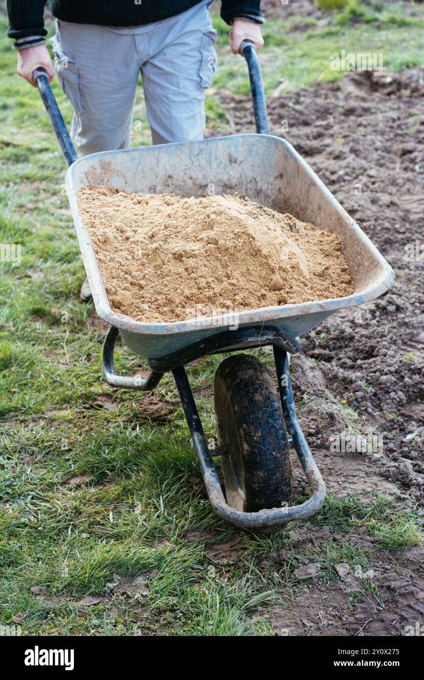 Man transporting sand in a wheelbarrow. Stock Photo