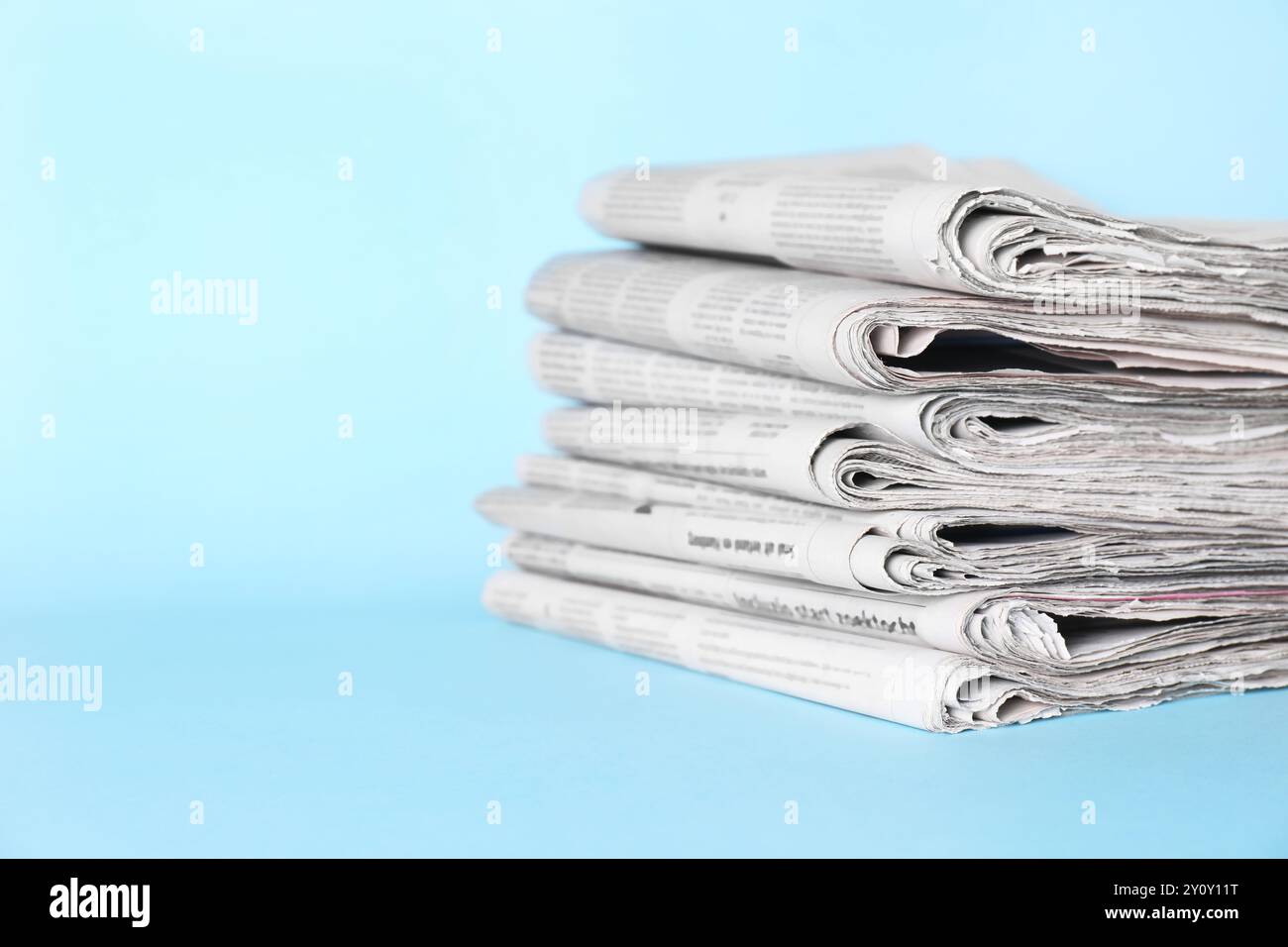 Stack of newspapers on light blue background, space for text Stock Photo