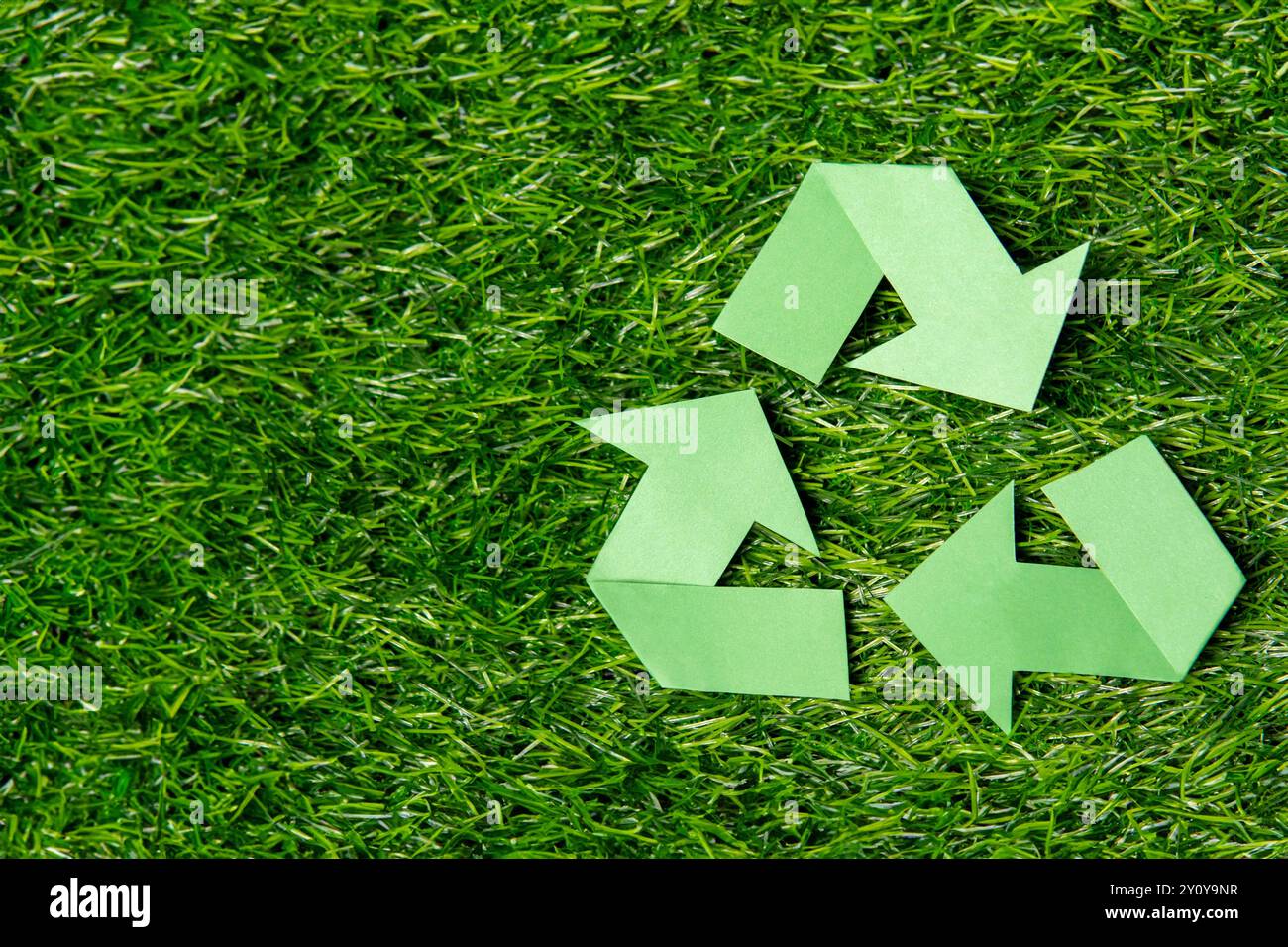 A green recycling symbol on a lush grass background with copy space ...