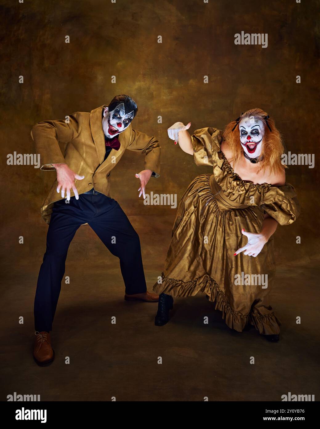 Clowns, dressed in vintage attire, striking comical poses together, with wide smiles and exaggerated gestures against vintage backdrop. Stock Photo