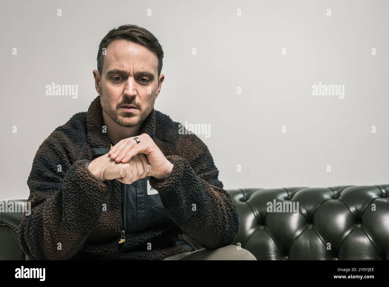 Portrait of man sitting on sofa thinking Stock Photo