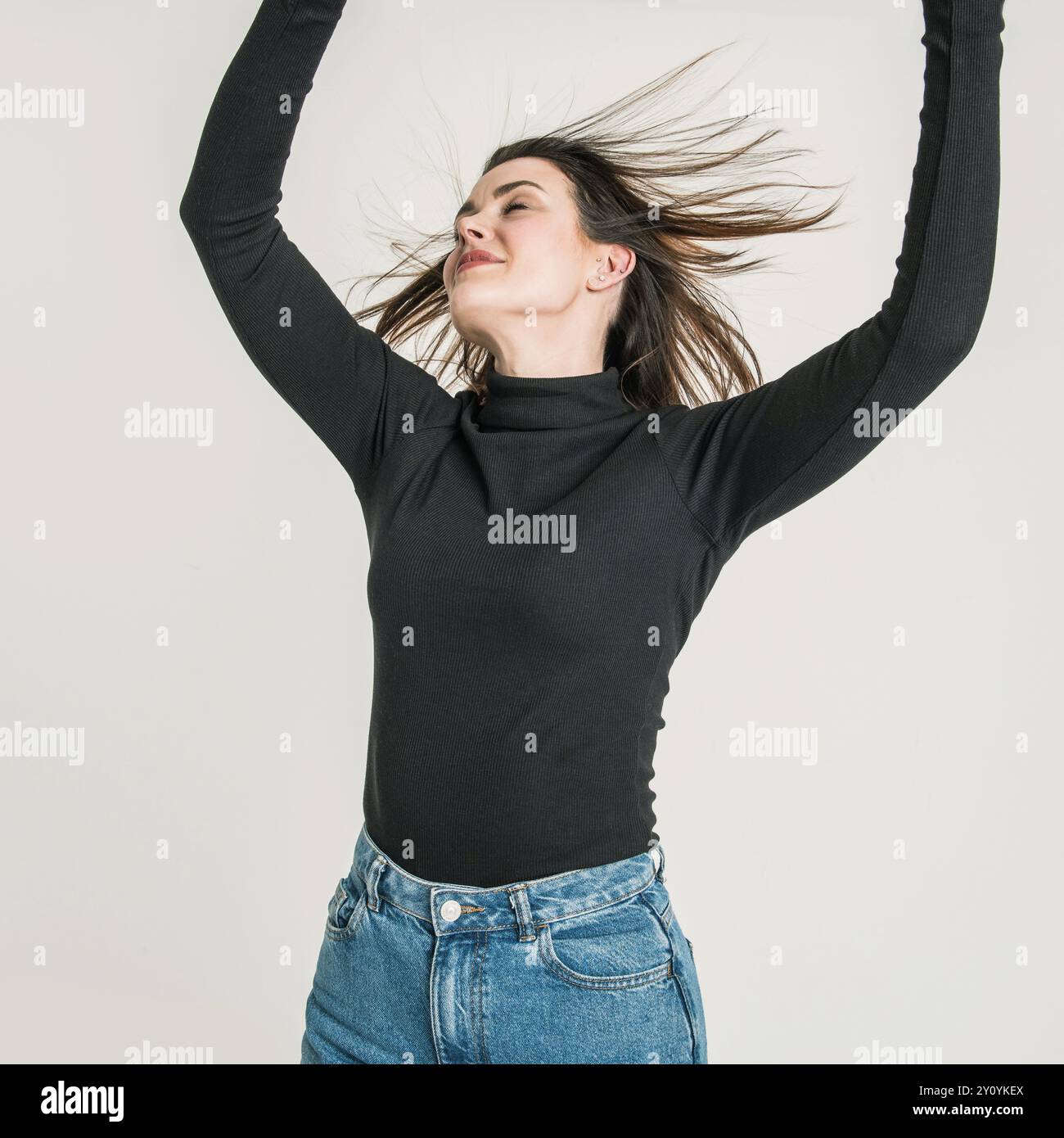 Studio portrait of woman lifting arms in air Stock Photo