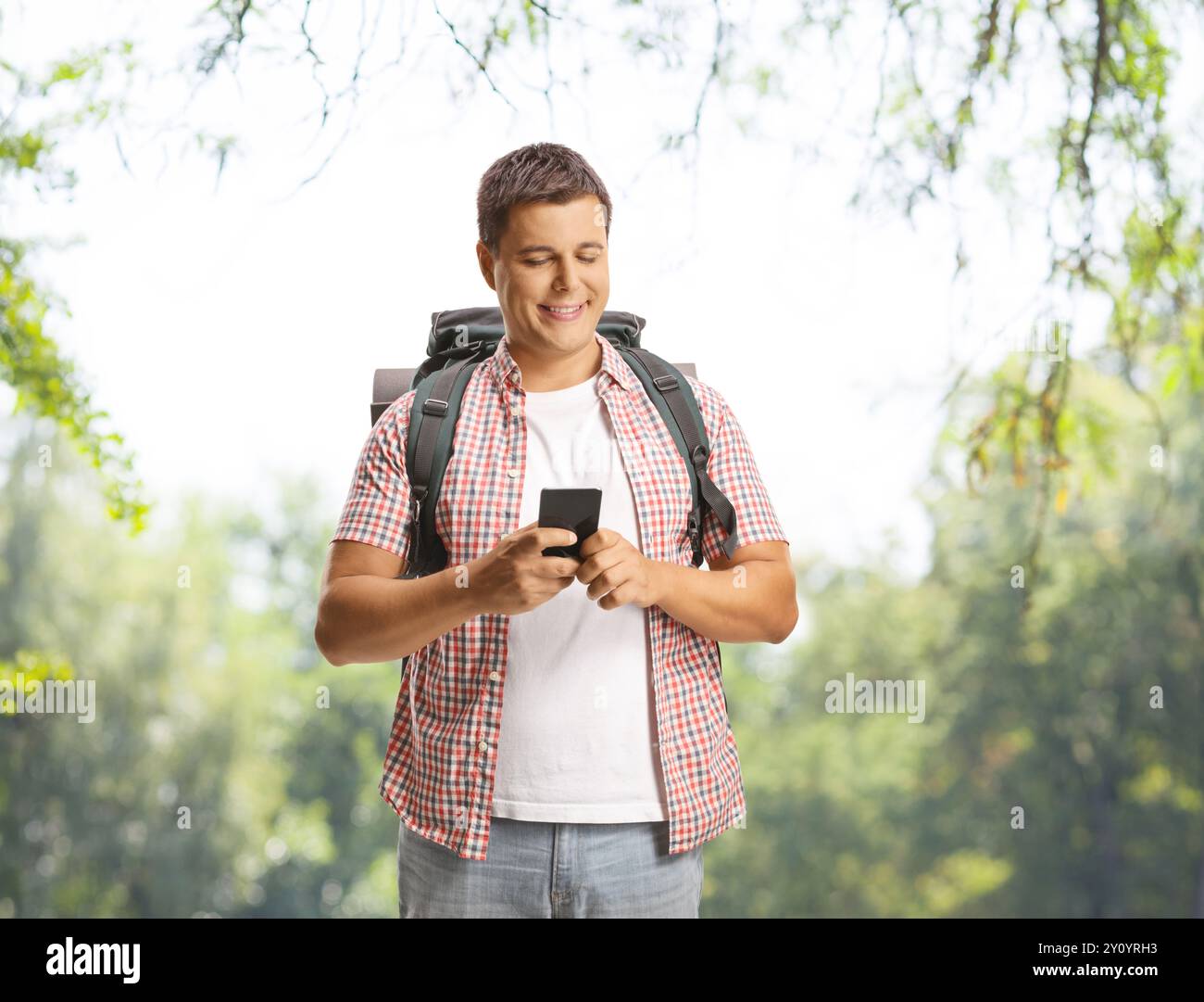 Guy with a backpack using a smartphone outdoors Stock Photo