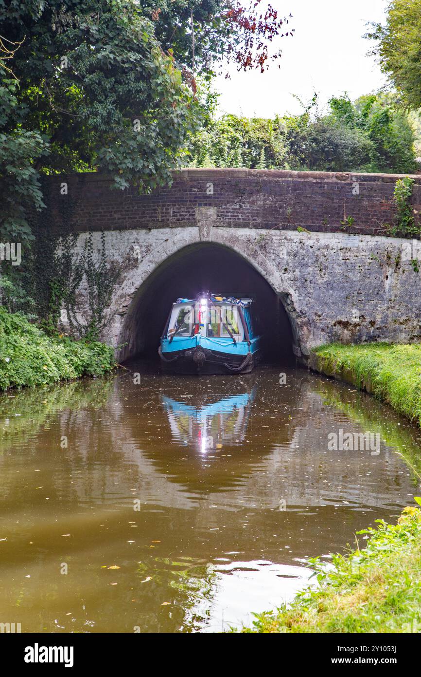 Canal narrowboat emerging from the northern end of the Barnton Tunnel on the Trent and Mersey canal in the Cheshire countryside Stock Photo