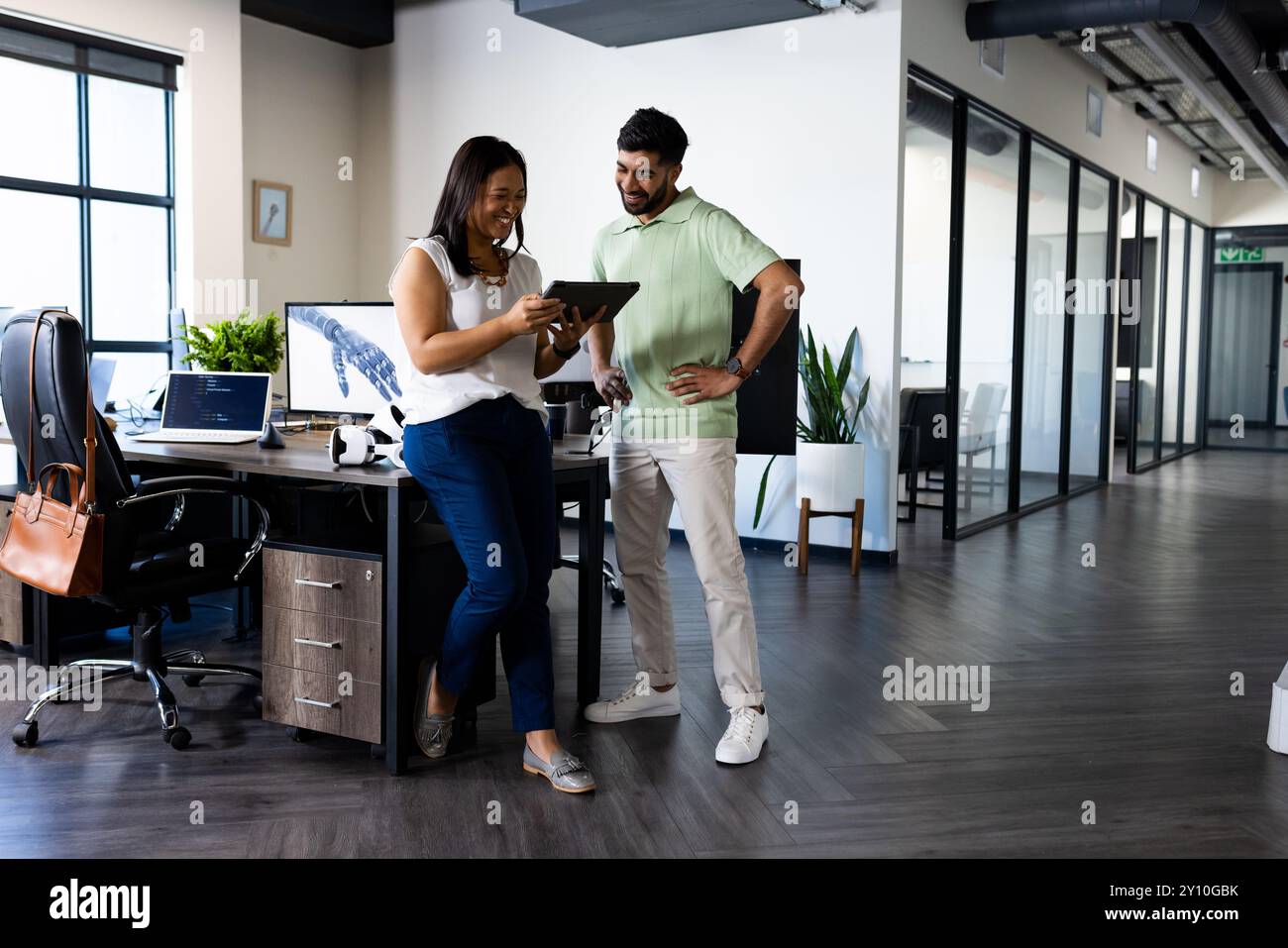 Collaborating in modern office, colleagues using tablet discussing project and smiling Stock Photo