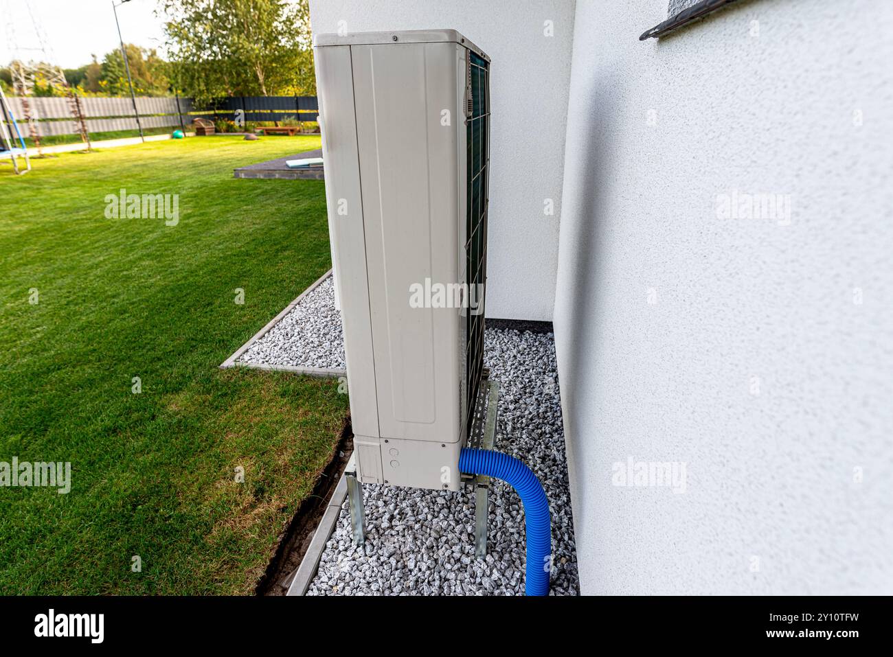 Two efficient outdoor heat pump units placed in front of the house. Stock Photo