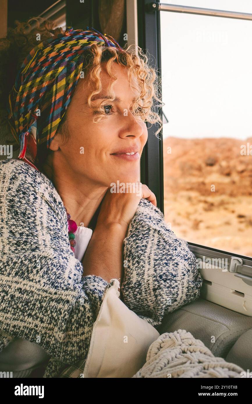 Woman sits happily in her motorhome and looks out through the window ...