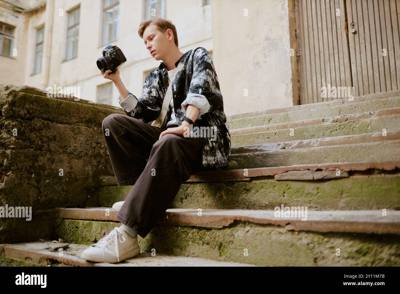 Young Man Holding Camera Sitting on Outdoor Steps Stock Photo - Alamy