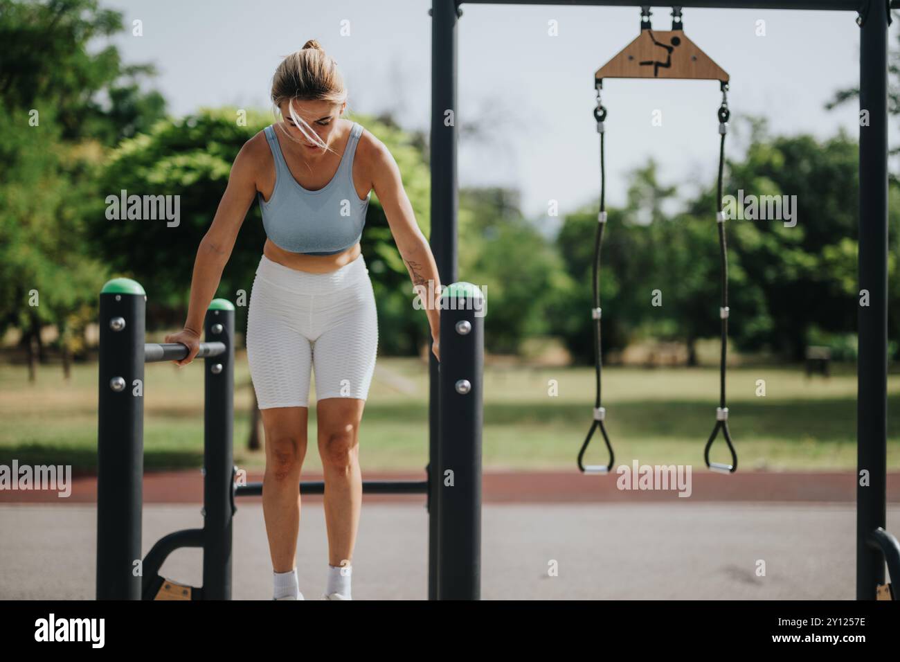 Woman performing calisthenics workout in sunny park using outdoor fitness equipment Stock Photo Alamy