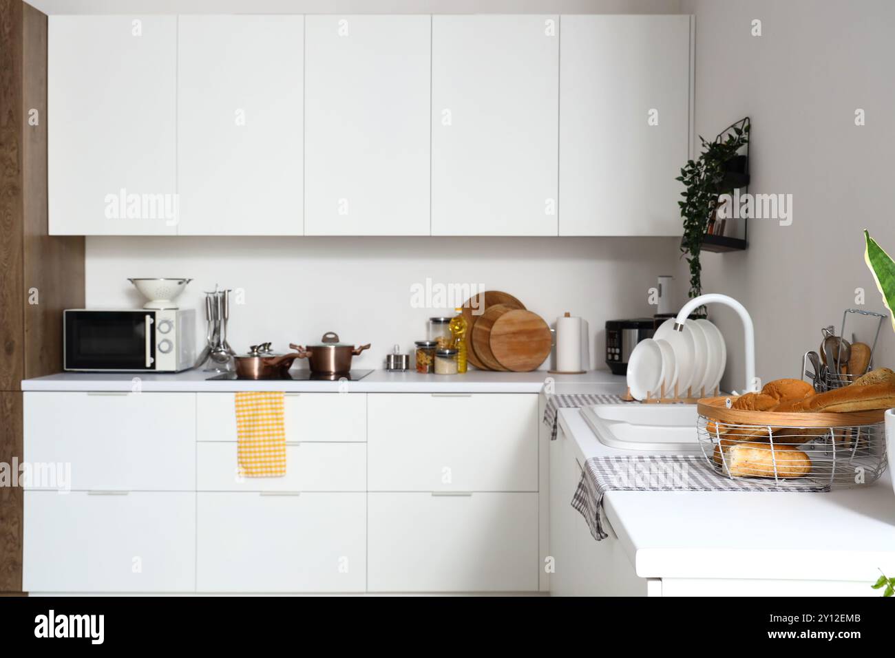 Interior of modern kitchen with white counters, microwave oven and ...