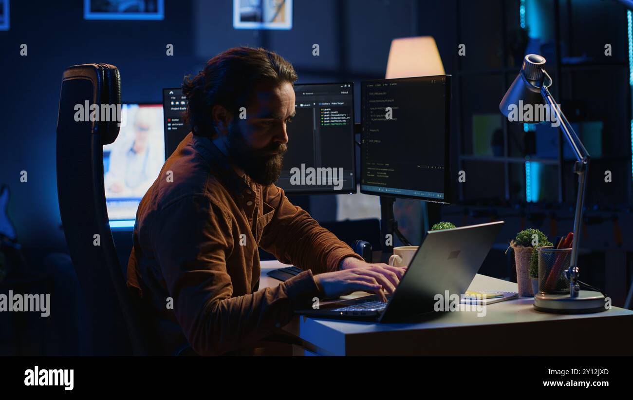 Computer scientist putting headphones on while developing code on PC, making time pass faster during remote job shift. IT admin doing multitasking in home office while listening music, camera A Stock Photo