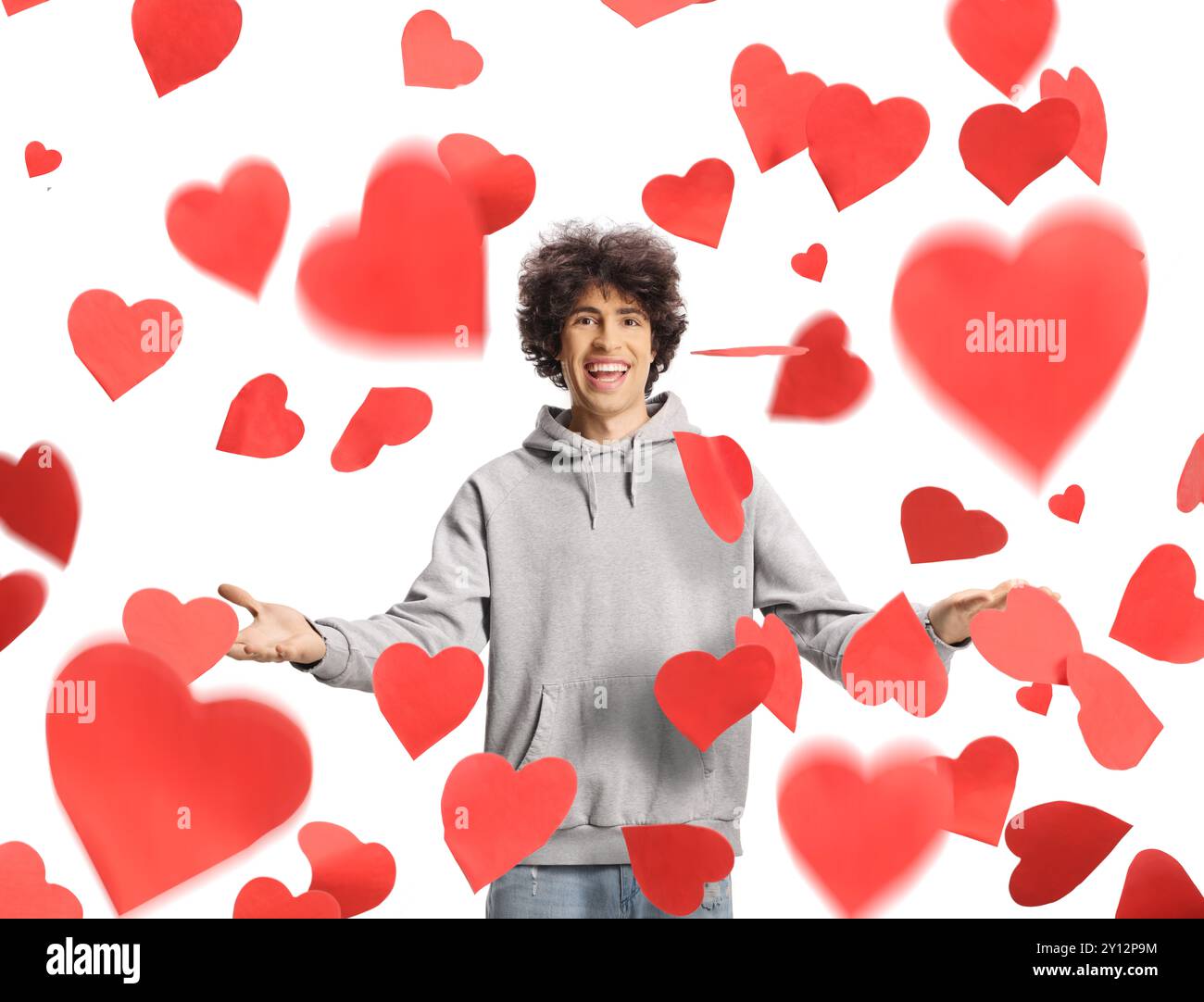 Young man standing under red falling hearts isolated on white background Stock Photo