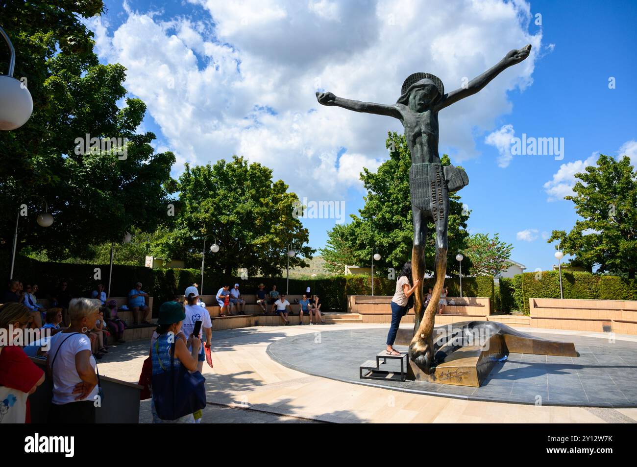 People venerating the statue of the Risen Christ in Medjugorje. The statue miraculously weeps drops of fluid from Jesus' right knee. Stock Photo