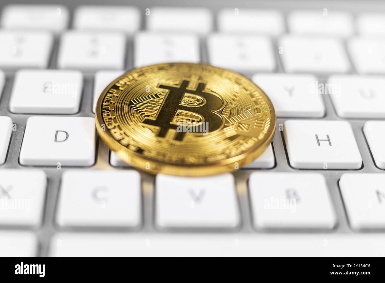 Bitcoin coin lying on white computer keyboard Stock Photo