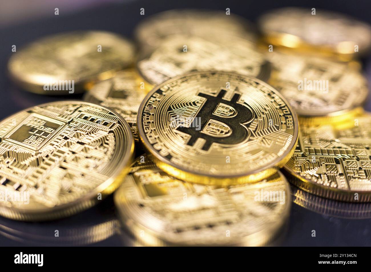 Stack of bitcoins lying on shiny dark surface Stock Photo