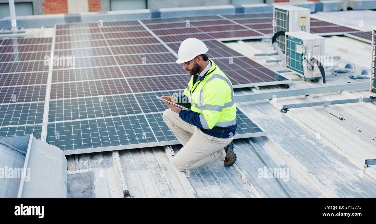 Technician, man and tablet for solar panels, energy saving and electricity or heating of eco friendly grid on rooftop. Engineering, digital technology Stock Photo