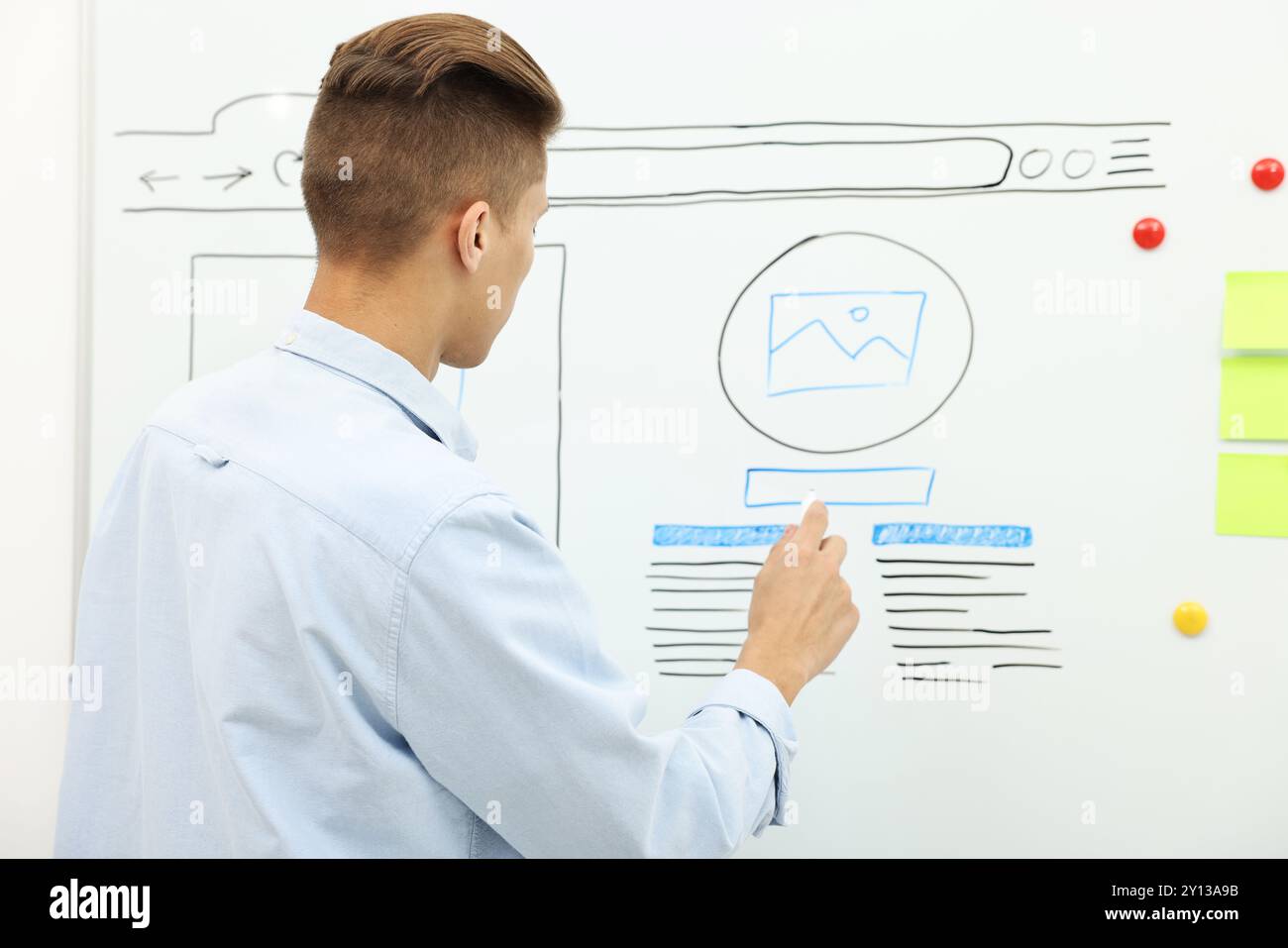 Developing UI design. Man drawing website wireframe on whiteboard indoors Stock Photo