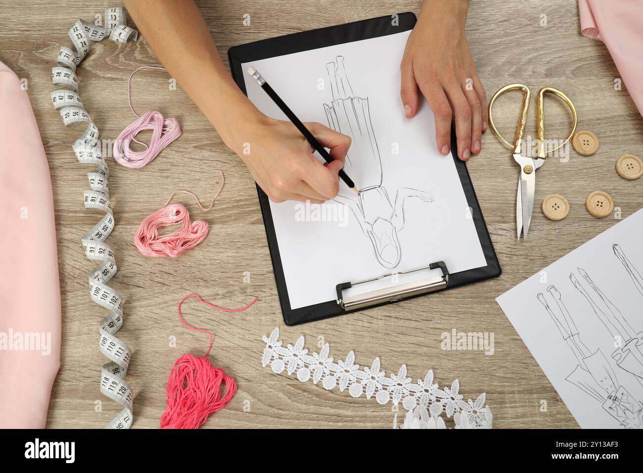 Fashion designer drawing sketch of stylish dress at wooden table, top ...
