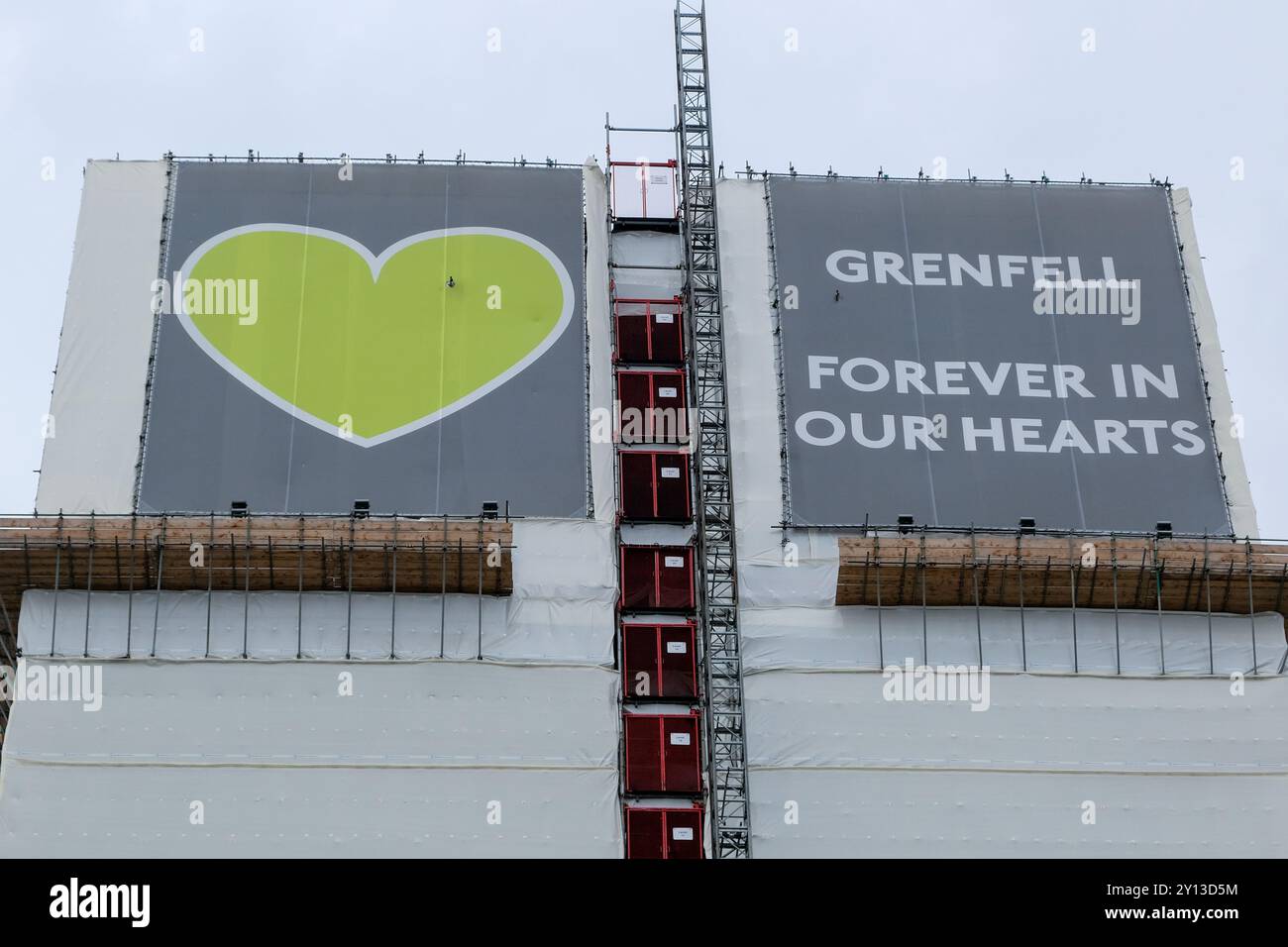 The top of Grenfell Tower covered by green hearts and the words, 'Forever in our hearts,' in memory of the 72 residents who perished in the fire. Stock Photo