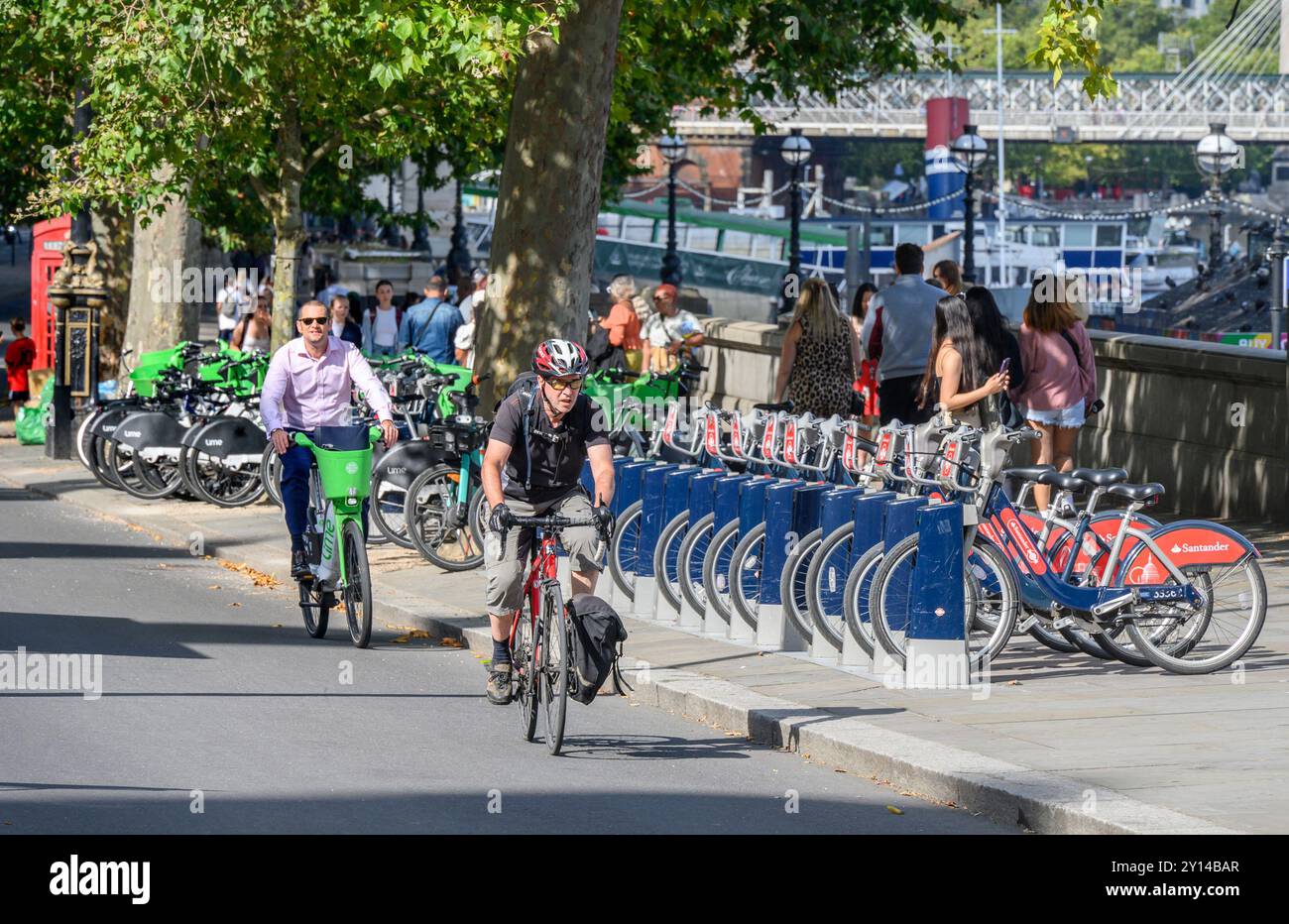 London, UK. Cyclists cycling past rows of rental bikes on the Victoria Embankment near Parliament, Westminster Stock Photo