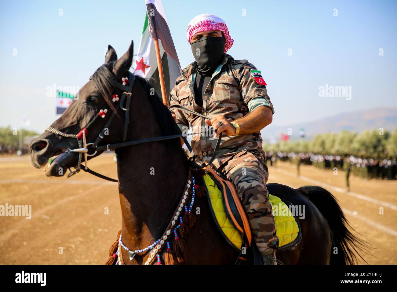 Aleppo, Syria. 06 July 2021. A military ceremony is held in the Afrin’s countryside in northern Syria for the graduation of 2,500 fighters from the Syrian National Army (SNA). Many fighters of the SNA marched in the Sheikh Hadid area of Afrin in the northwest of Aleppo, while others rode motorbikes and horses. Images of killed fighters of the Syrian National Army were displayed at the event, as well as the Syrian opposition's flag and the Turkish flag. The SNA is a coalition of armed Syrian groups opposed to the government of President Bashar Al-Assad and allied to Turkey. The head of the Syri Stock Photo