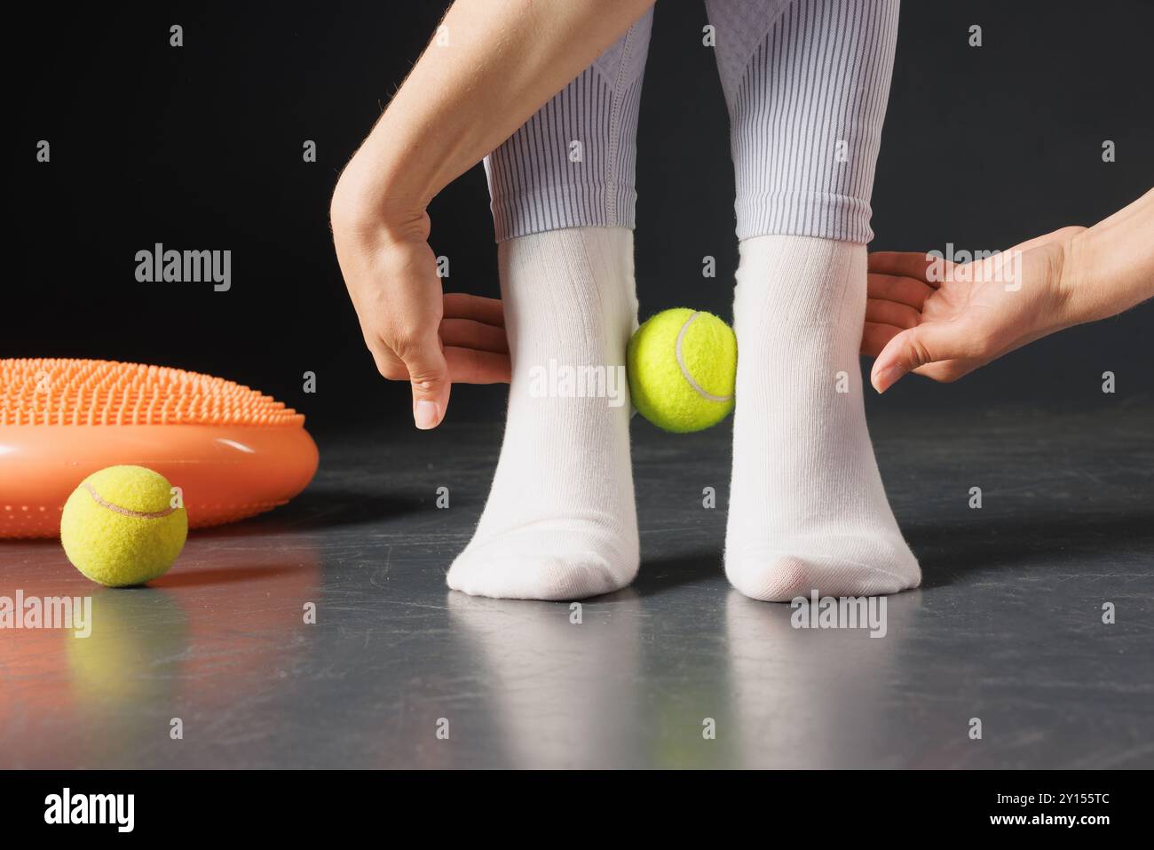 Strengthening the ankle joint with a tennis ball, a therapist is treating the legs, a close-up foot massage Stock Photo