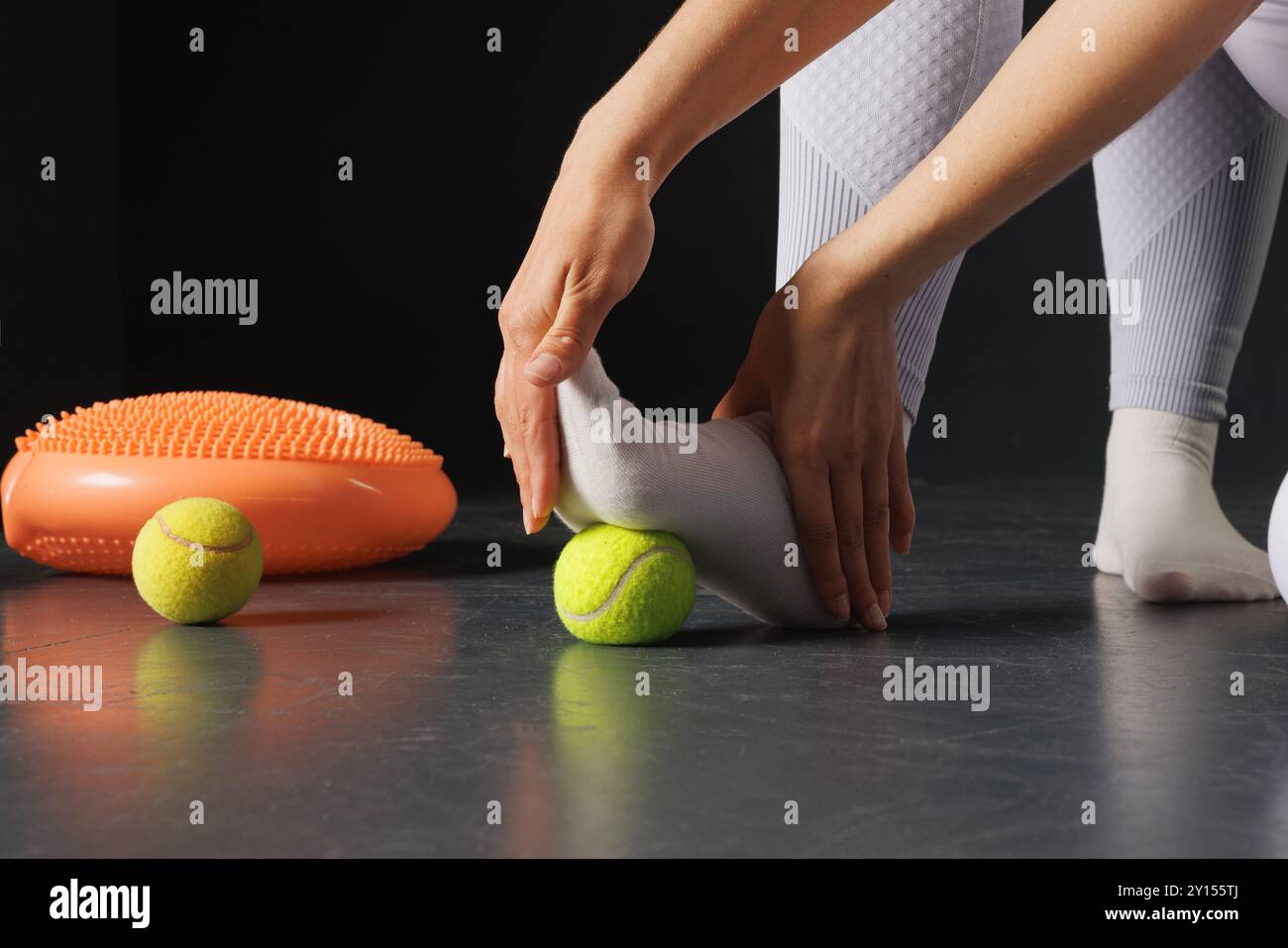 Strengthening the ankle joint with a tennis ball, a therapist is treating the legs, a close-up foot massage Stock Photo