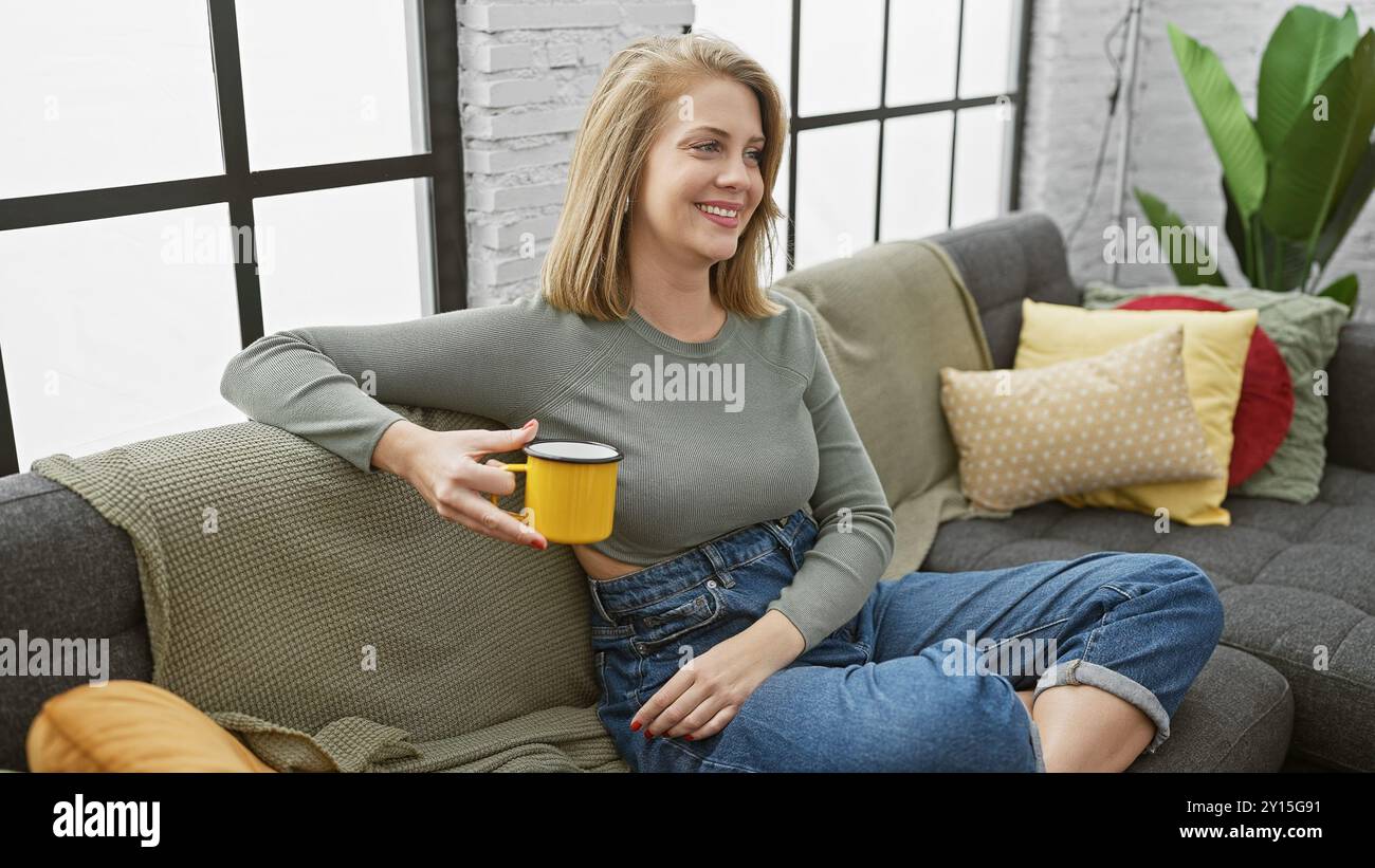 Blonde woman relaxing with coffee on sofa in a cozy living room Stock ...