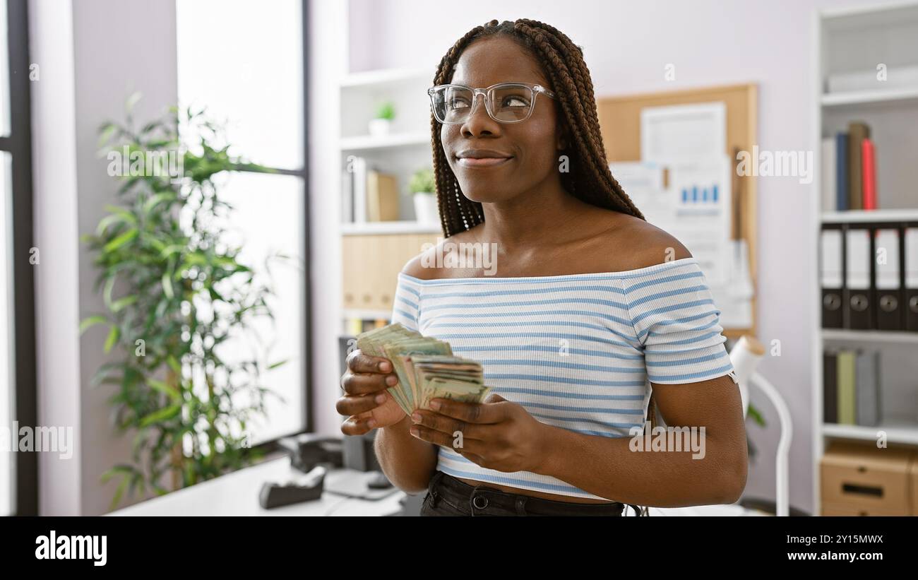 African american woman with braids holding uae dirhams in a modern ...