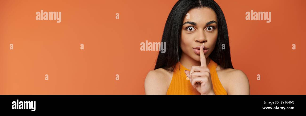 A woman playfully asks for silence with a finger on her lips. Stock Photo