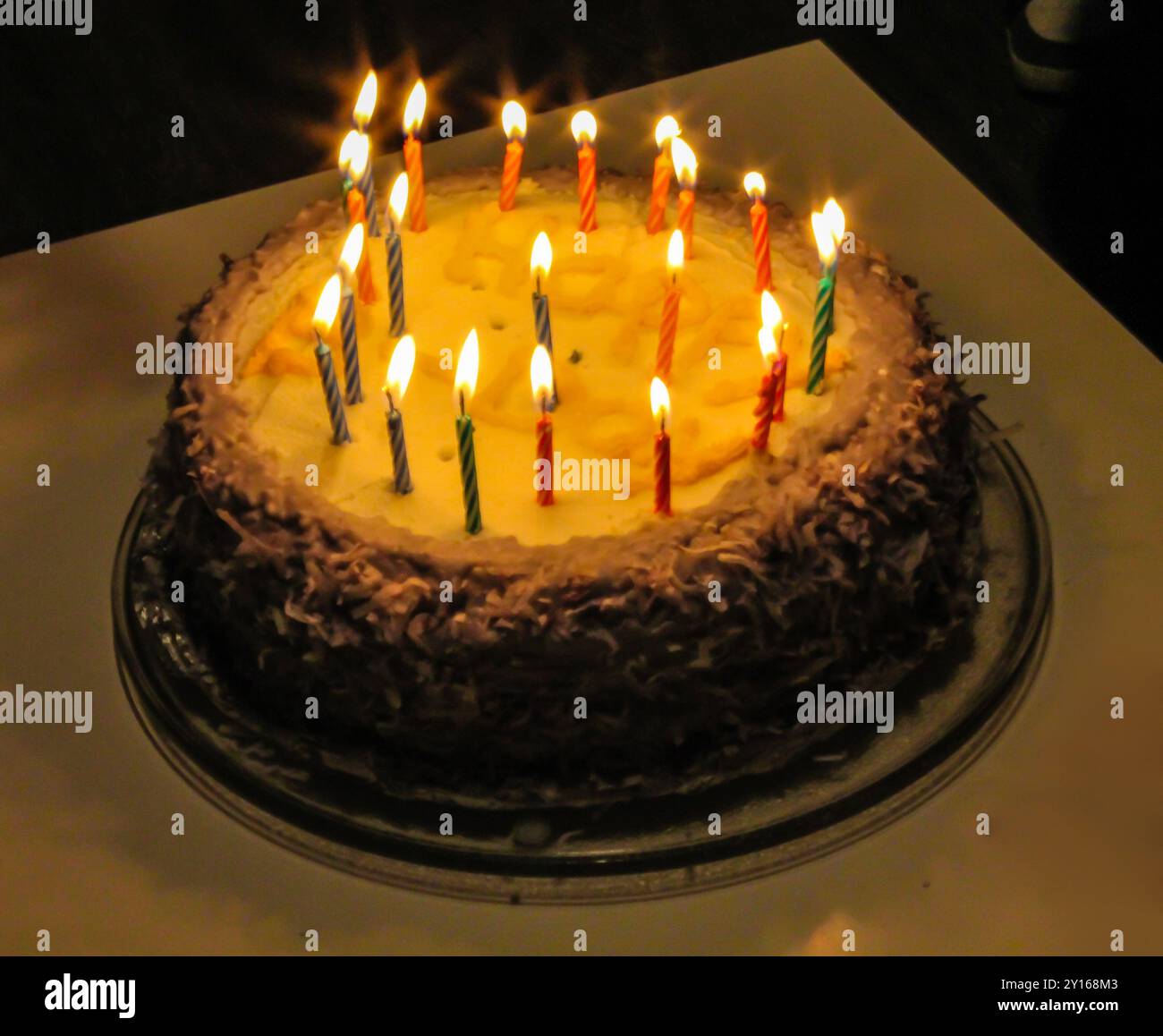 A beautifully decorated birthday cake with lit candles on top, set on a ...