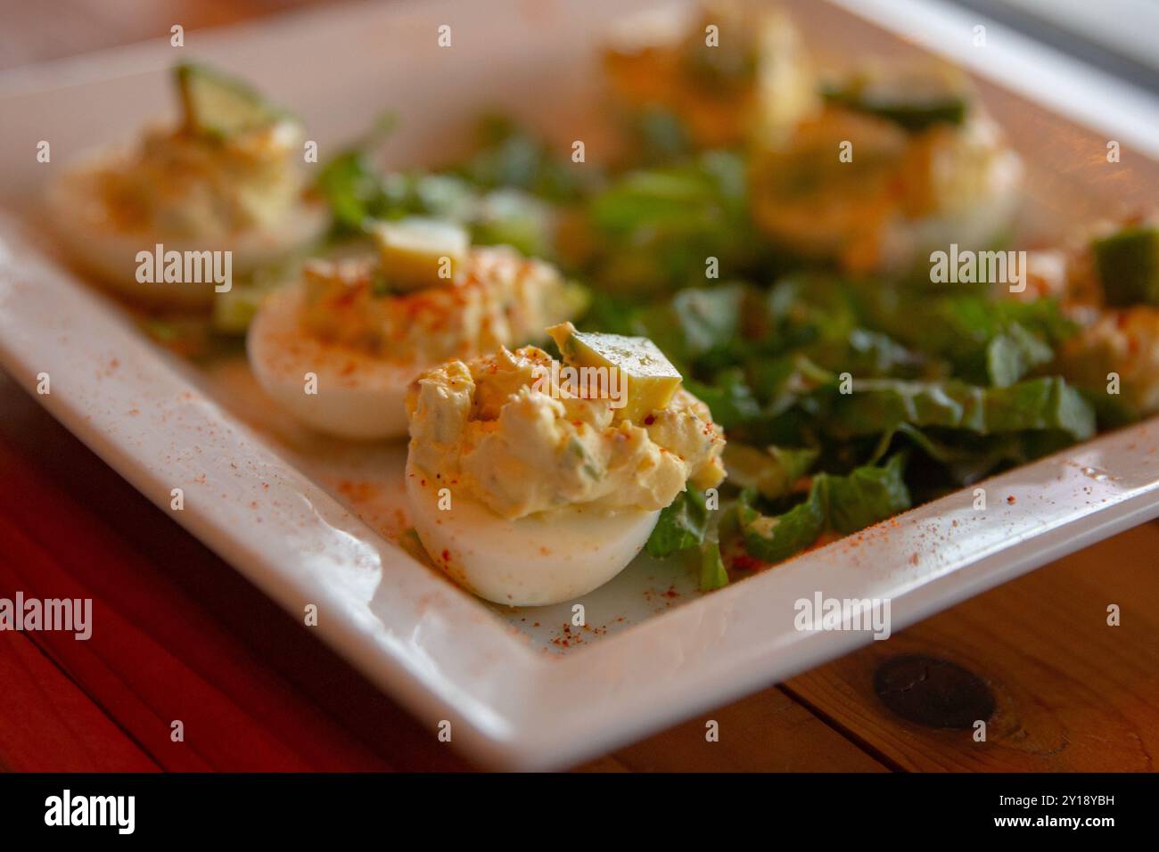 Avocado topped deviled eggs with salad Stock Photo