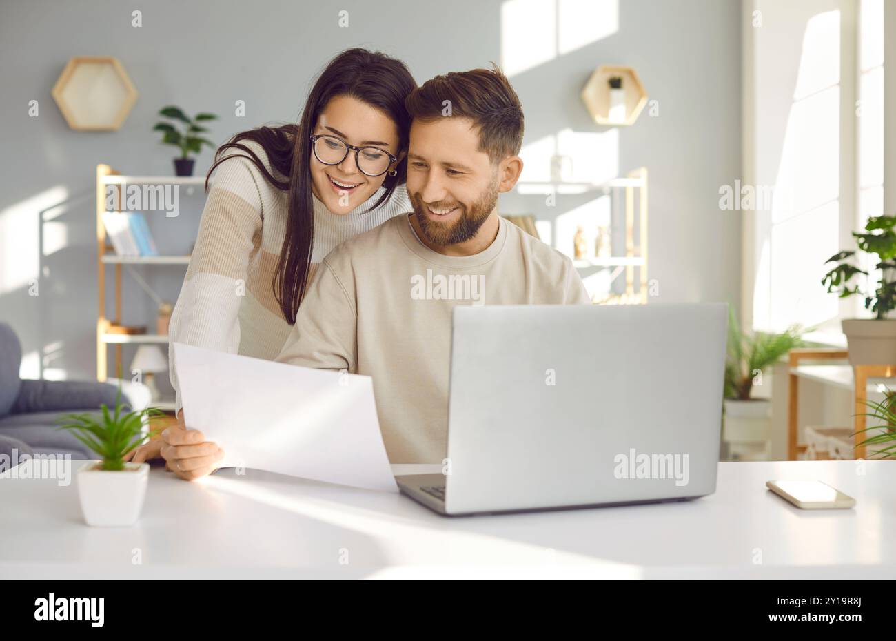 Young couple using laptop, checking financial documents at home Stock Photo