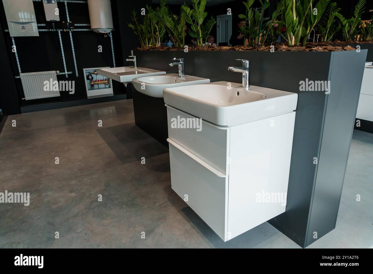 Modern Bathroom Showroom with Sleek Sink Fixtures and Vibrant Greenery Display. Stock Photo