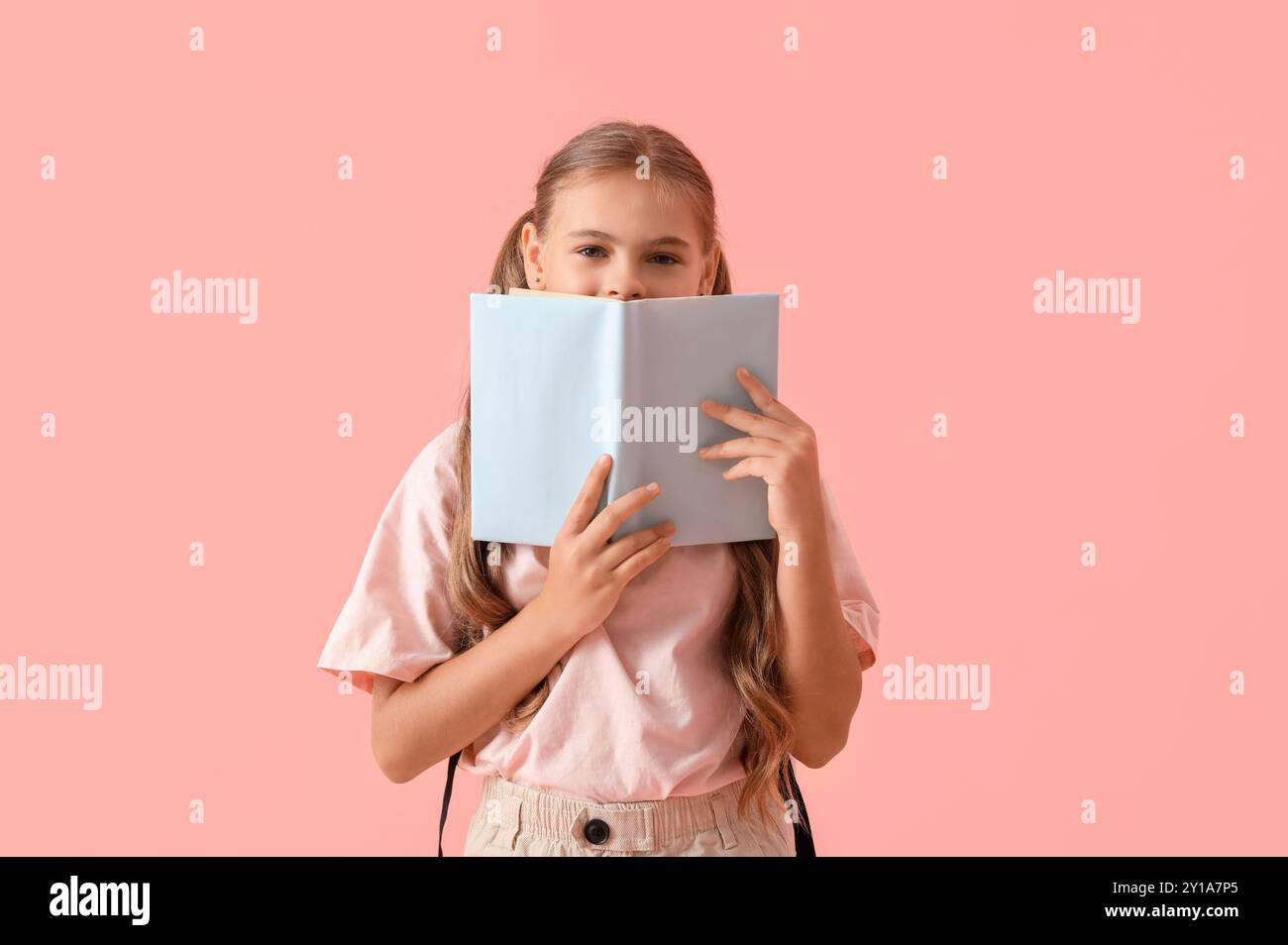 Cute schoolgirl with book on pink background Stock Photo - Alamy
