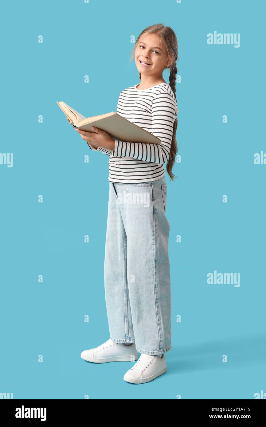 Cute schoolgirl with book on blue background Stock Photo - Alamy