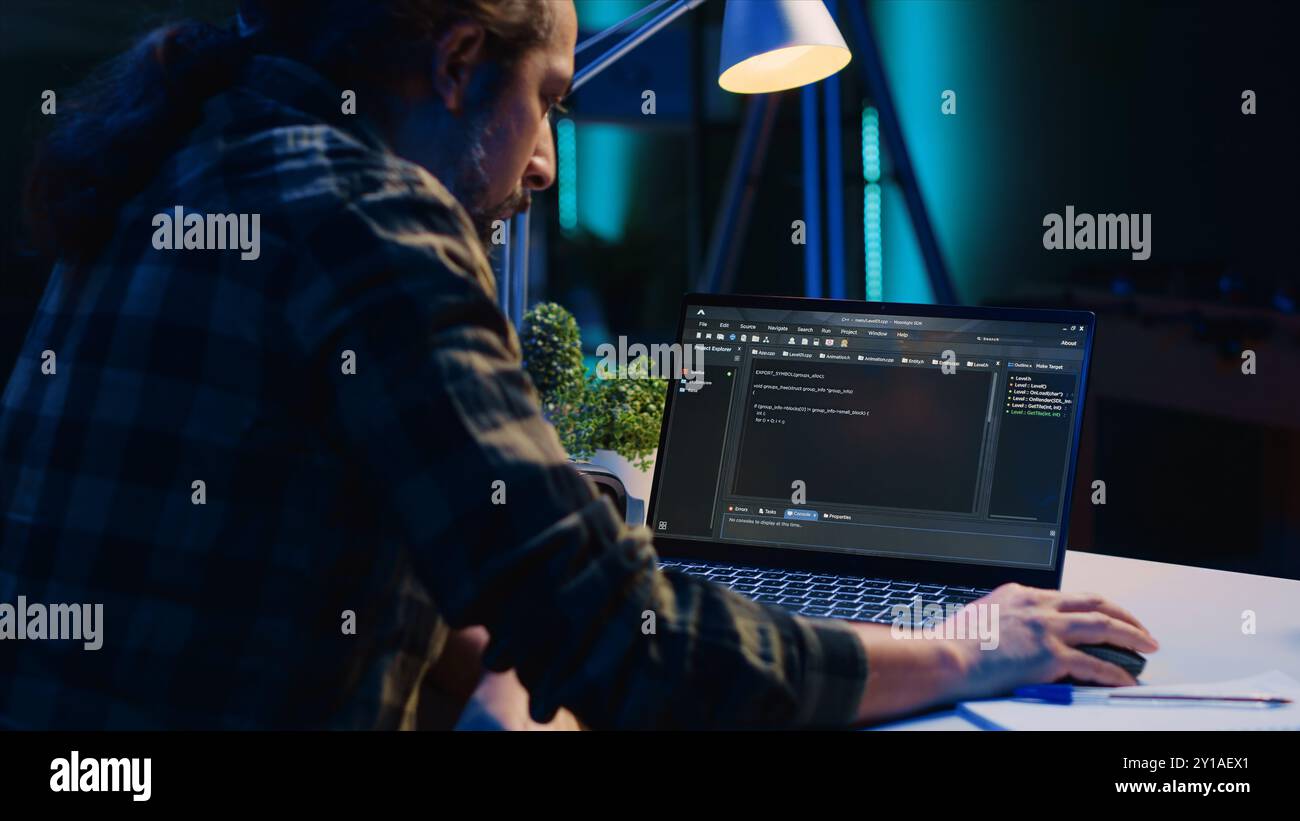 Skilled computer scientist writes code on laptop screen while in living room office using programming languages. Self employed IT specialist working on fixing database errors from home, camera A Stock Photo