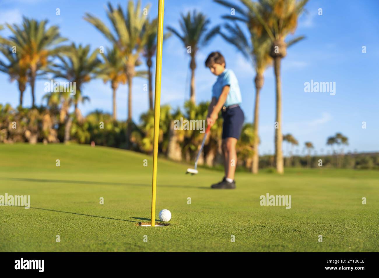 Horizontal full length photo of a young male golfer making a put Stock Photo