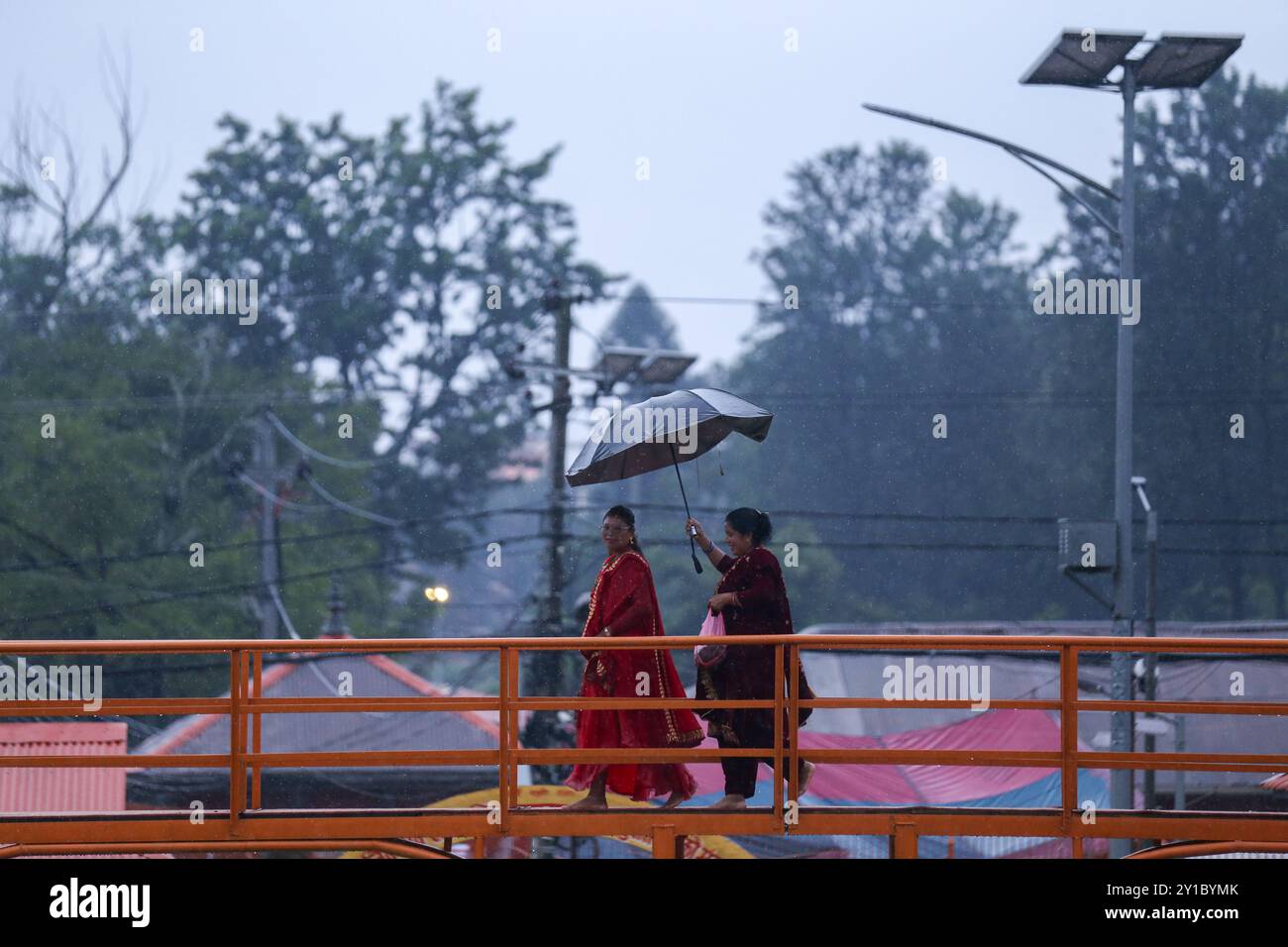 Fasting Nepali Hindu devotees rush towards Pashupatinath Temple in Kathmandu, Nepal, on September 6, 2024, to perform rituals on the occasion of the Teej festival. As per tradition, women on this third day of the dark half of the lunar month that falls in the Nepali month of Bhadra observe fasting and wish for a prosperous life while observing the festival. According to the 'Skanda Puran' (a religious scripture of the Hindus), this festival gets the name 'Haritalika Teej' as it is on this very day in the 'Satya Yug' (golden epoch of truth) that the daughter of the Himalayas, Parvati, is hidden Stock Photo