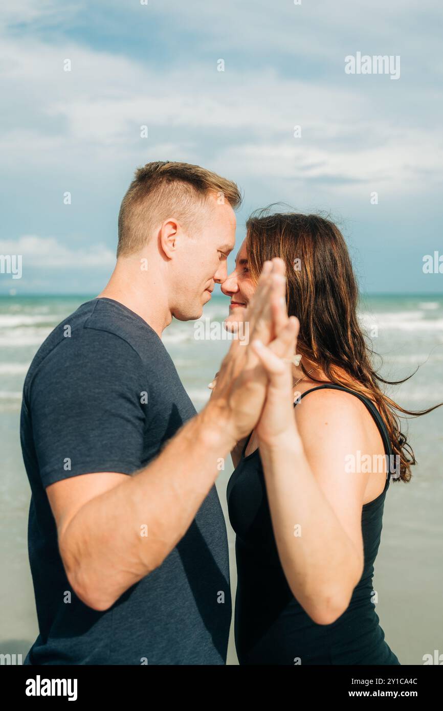 A couple shares an intimate moment on the beach, holding hands Stock ...