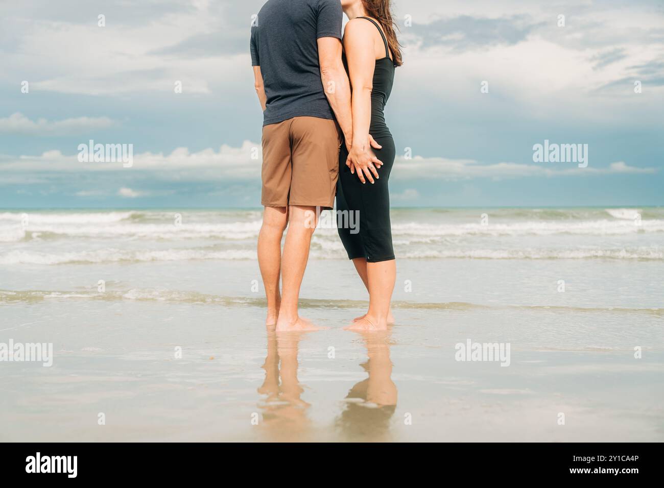 Couple standing on the beach, holding hands with reflection Stock Photo