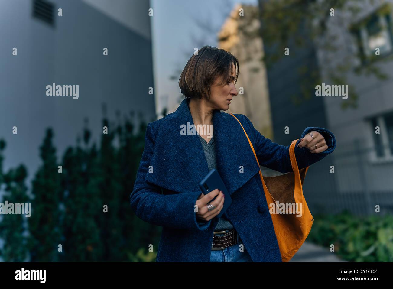 Young woman looking inside bag while holding smartphone Stock Photo