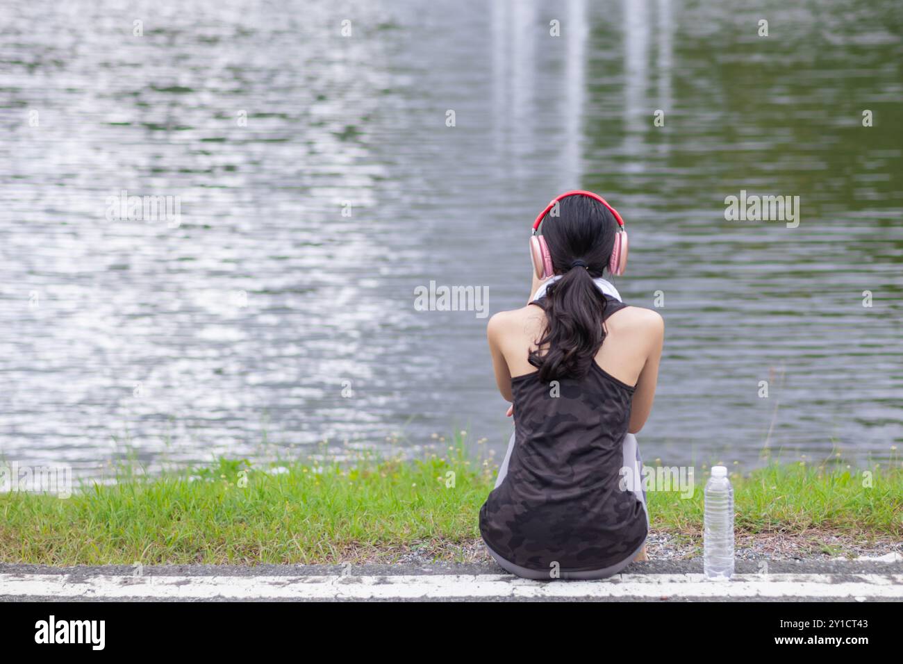 Asian woman sits on side of the road after running long distance and ...