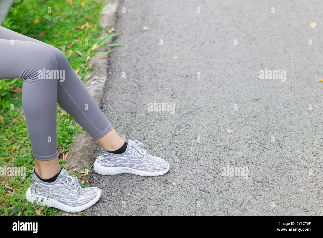 Asian woman sits on side of the road after running long distance and ...
