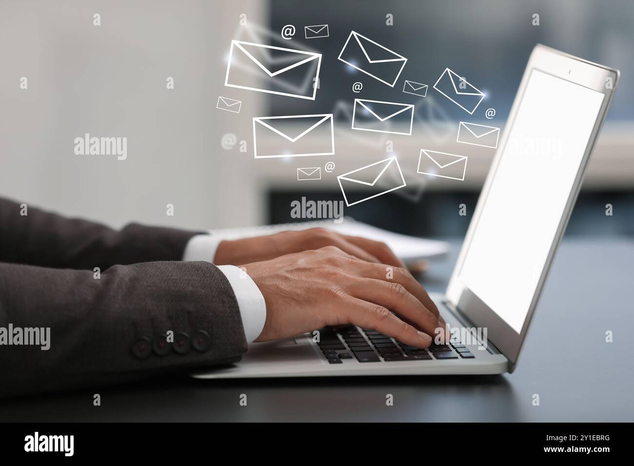 Man using laptop at table, closeup. E-mail address signs and envelopes over computer Stock Photo