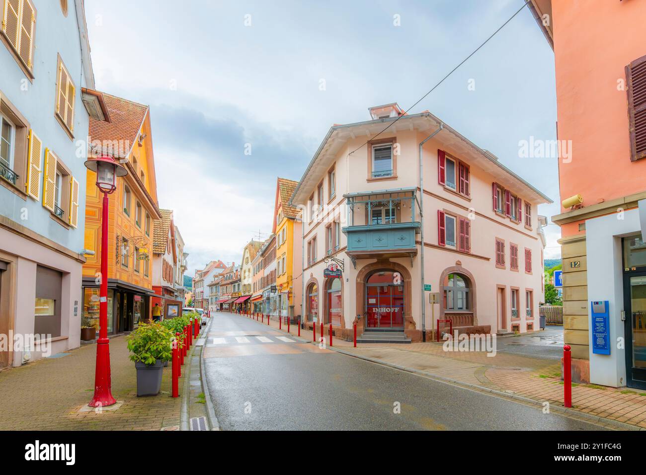 The picturesque colorful Grand Rue street with sidewalk cafes and shops in the historic old town of Munster, France, in the Alsace wine region. Stock Photo