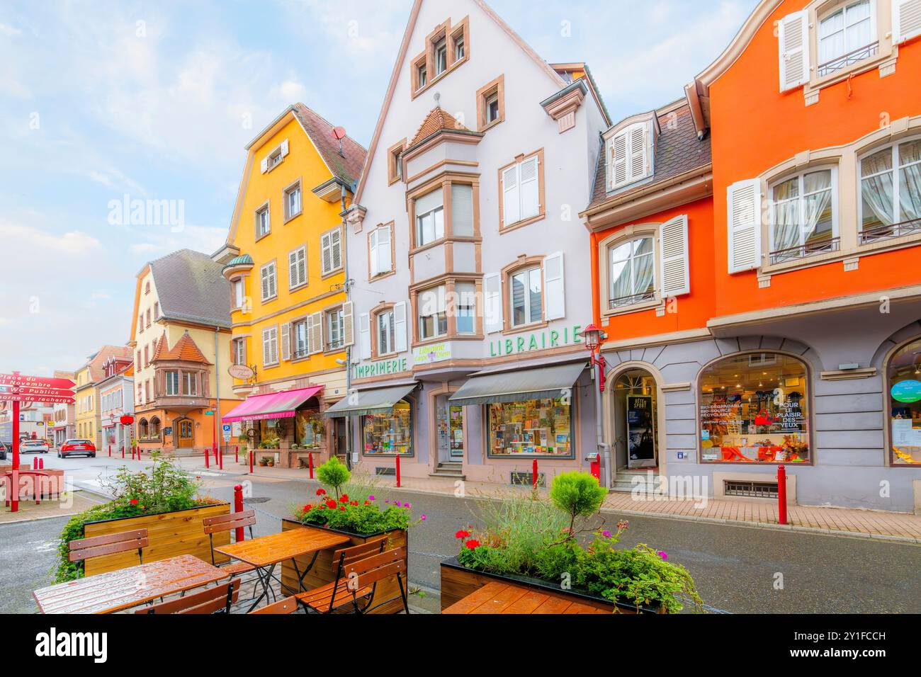 The picturesque colorful Grand Rue street with sidewalk cafes and shops in the historic old town of Munster, France, in the Alsace wine region. Stock Photo