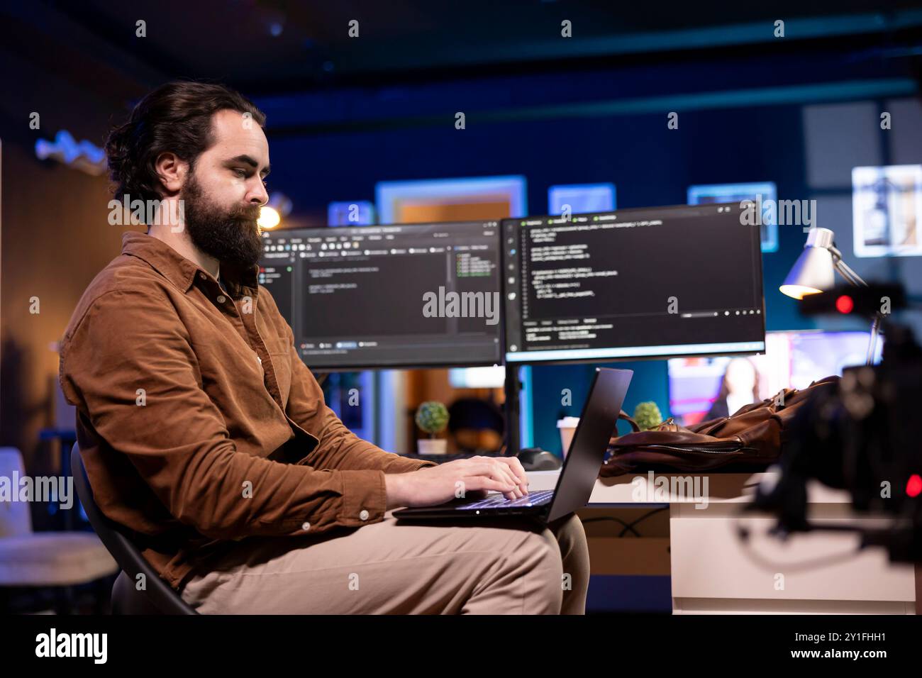 Programmer doing software debugging using laptop, checking errors in lines of code displayed on computer monitors. Man working from home fixing coding mistakes using notebook device Stock Photo
