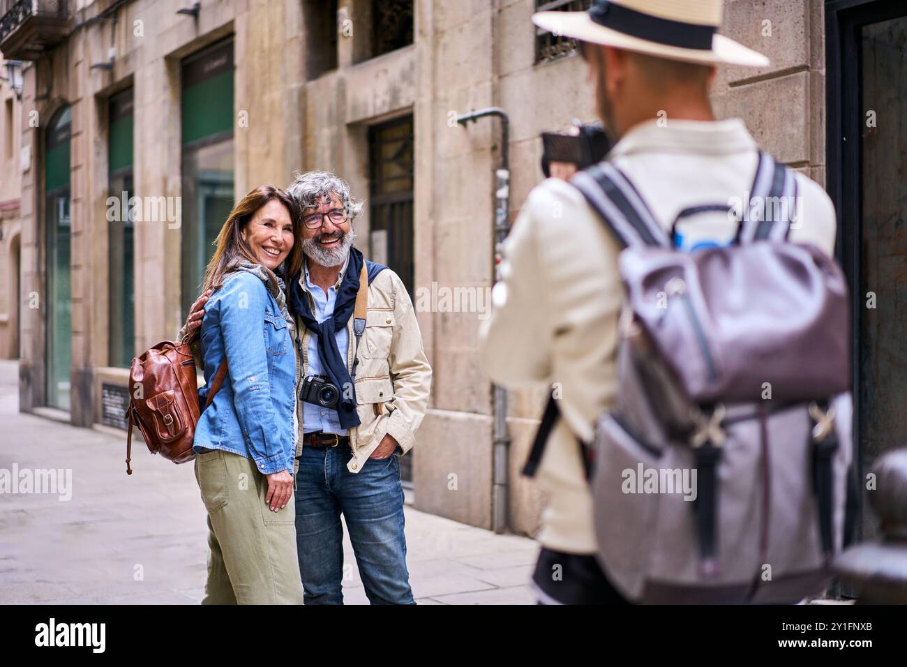 Young male photographer taking holiday photo happy elderly tourist couple posing smile city street Stock Photo