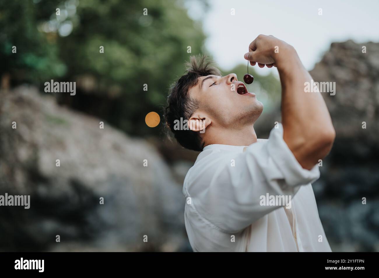 Young man enjoying fresh cherries in nature Stock Photo